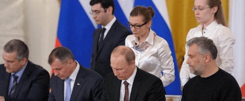 Russian President Vladimir Putin signs the treaty annexing Crimea in 2014, joined by pro-Russian officials during the Kremlin ceremony.